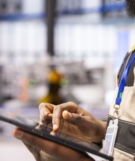 Industrial automation expert utilizes digital tools to streamline smart factory operations. Closeup of engineer analyzing system data on tablet, finetuning robotic automation in production line.